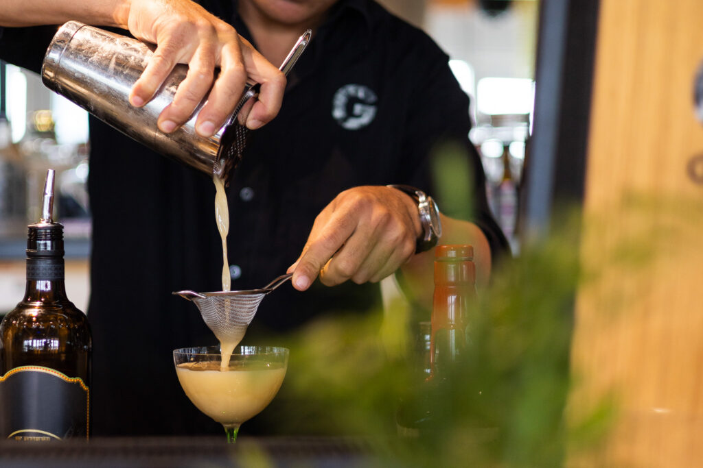 Ein Barkeeper in der GINN Bar in Hamburg, der gerade ein Cocktail abseiht.