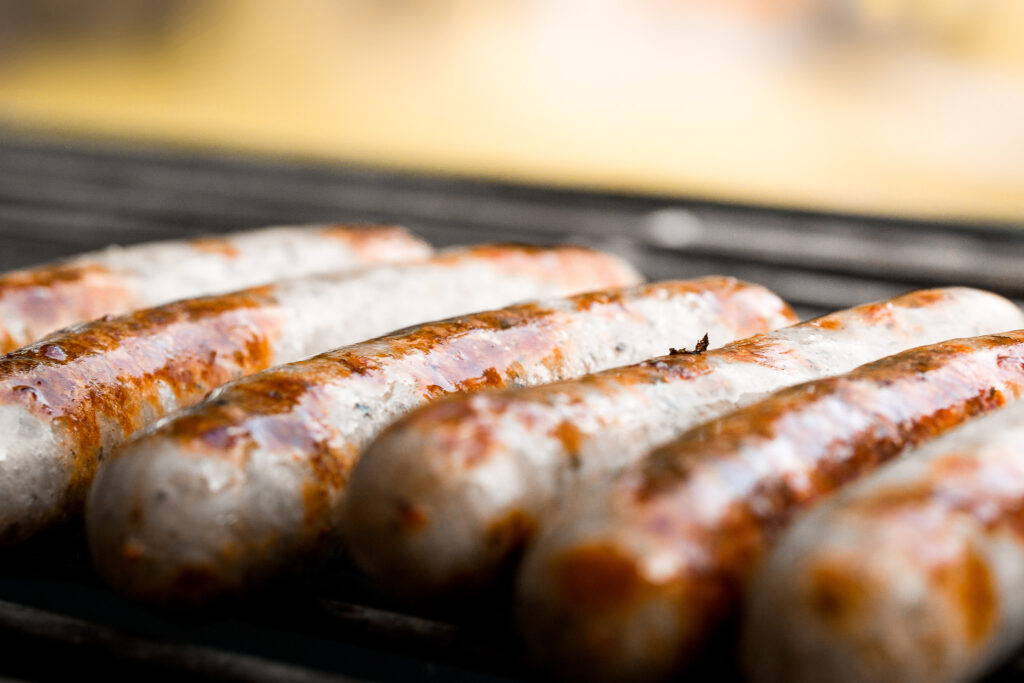 Eine Reihe von Bratwürstchen, die auf einem Grill liegen und brutzeln.